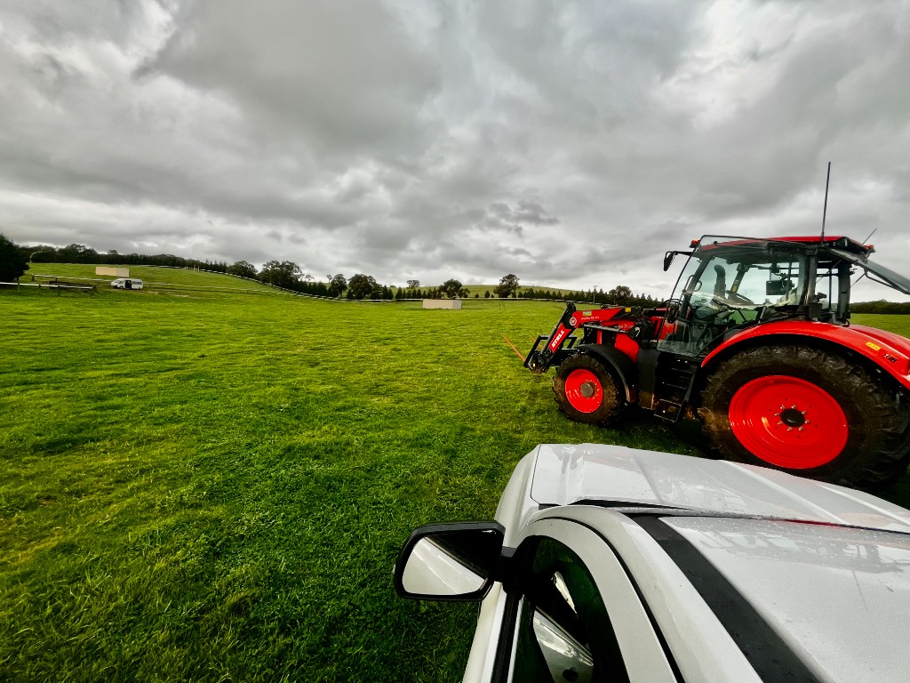 Red tractor in a green field, seen from the car